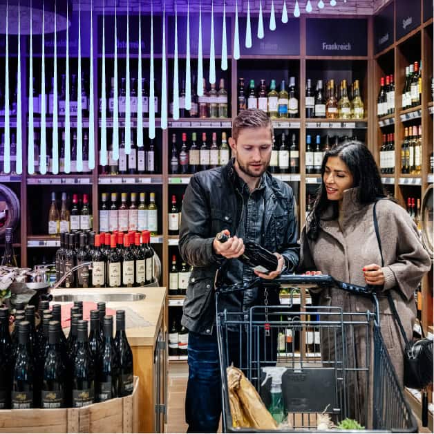 Man and woman shopping at a wine and spirits store looking at a bottle