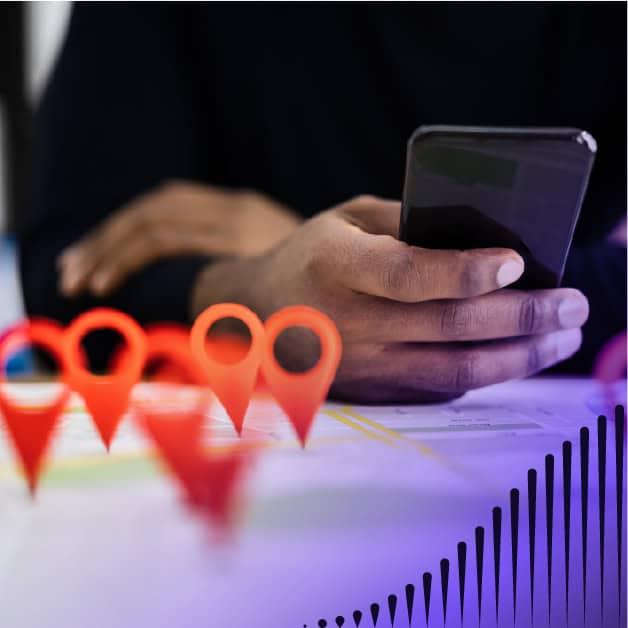 Person holding a smart phone with location pins on the table in front of him