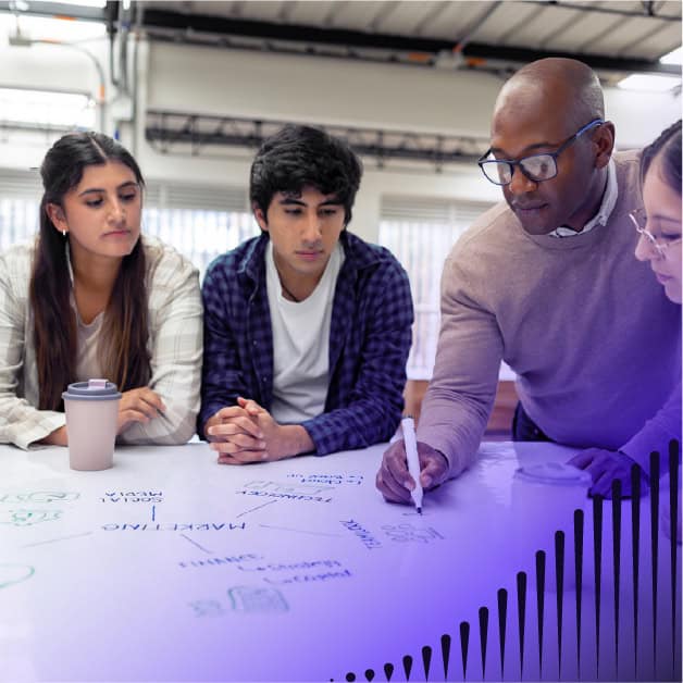 Four people leaning over a marker board working