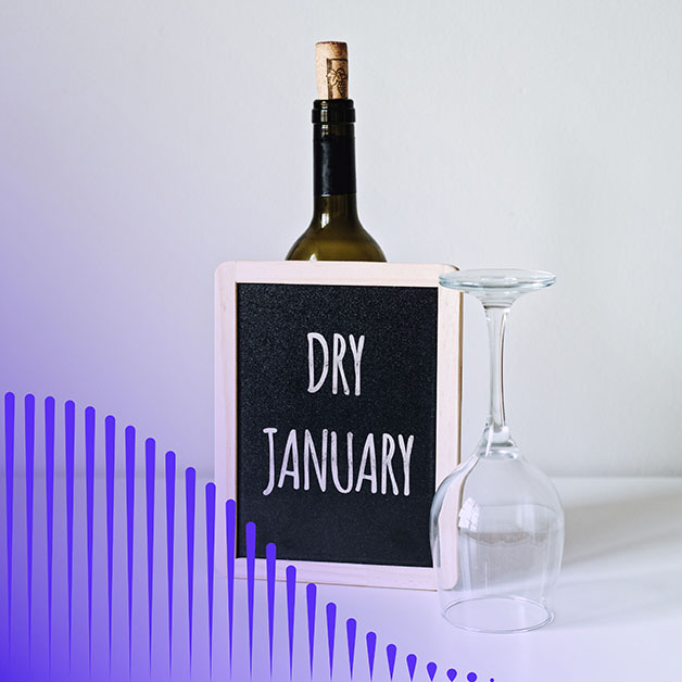 Small blackboard that says "Dry January" propped up against a wine bottle with wine glass beside it