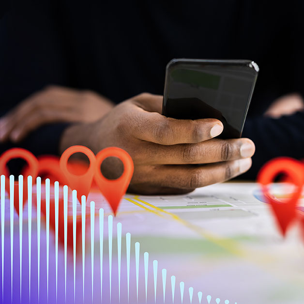 Person's hand holding phone with location pins coming off of a map