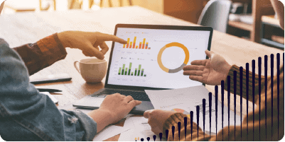 Three people gather around a laptop screen that displays two bar graphs and one pie chart