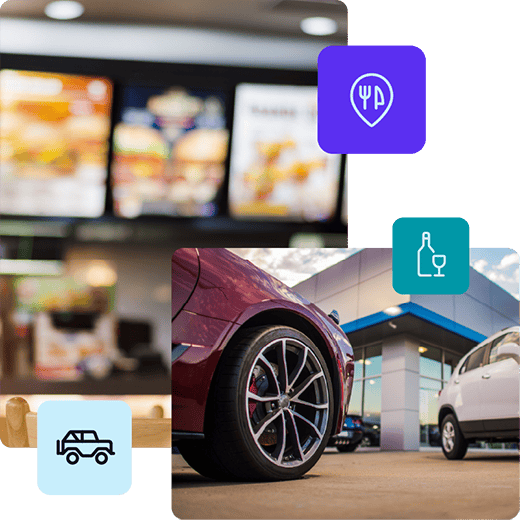 In the background of the photo, there is an out-of-focus menu board at a fast food restaurant. In the foreground, there is a red car on the left, a white car on the right, and a white building with blue trim representing a dealership in the middle.