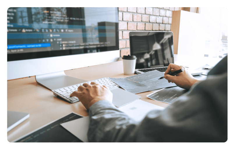 Man sitting in front of a computer and monitor working on plans